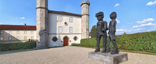 Das Gebäude des Kunstmuseums Schloss Derneburg mit einem modernen Kunstwerk im Vordergrund.